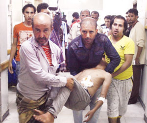 يمنيون يحملون مدنيا أصيب في قصف عشوائي على تعز (رويترز)